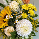 Bouquet of flowers with sunflowers, white and yellow chrysanthemums, and greenery.