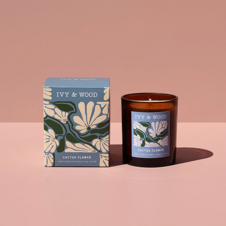 IVY & WOOD candle and packaging on a pink background
