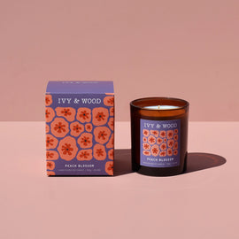 IVY & WOOD candle and packaging on a pink background