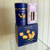 Monista tea set with blue canister and floral packaging on a white background